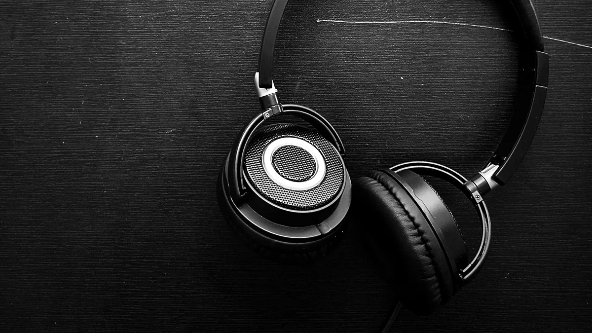 Over-ear headphones resting on a dark wooden surface.
