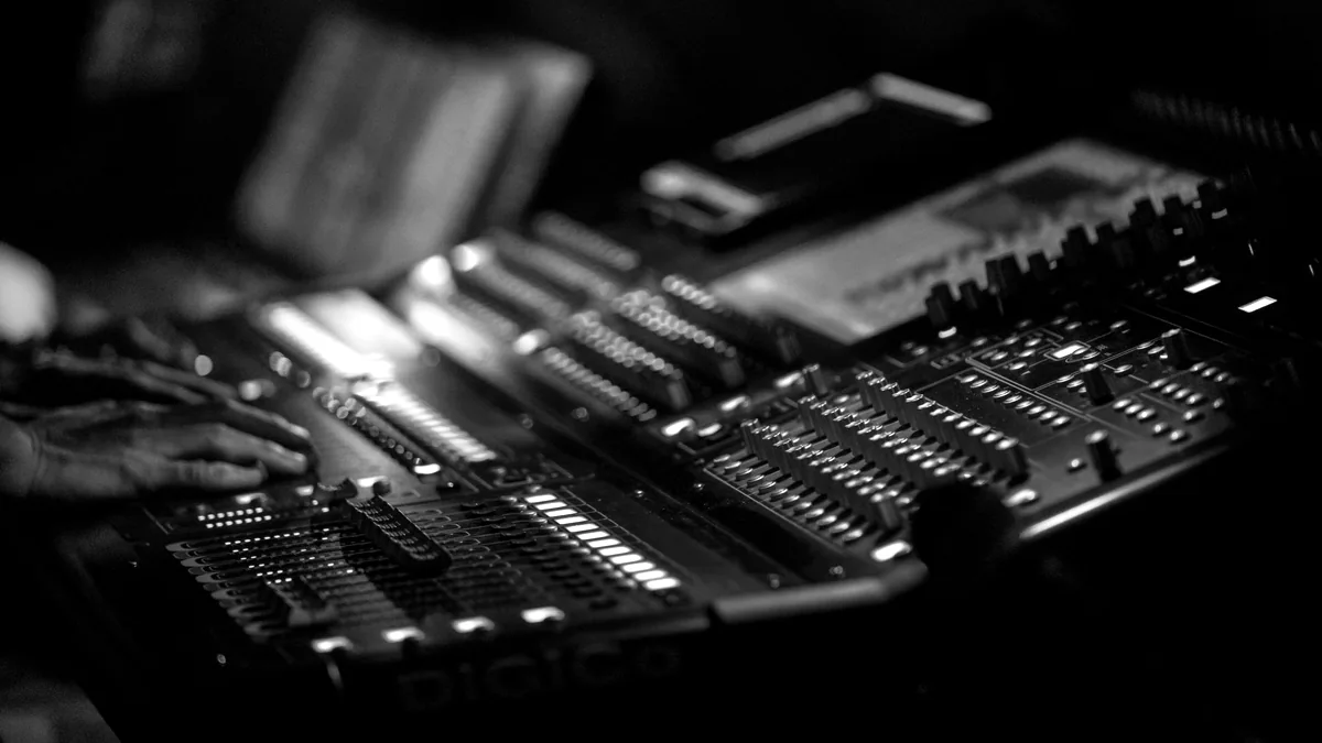 Hands adjusting faders on a mixing console.